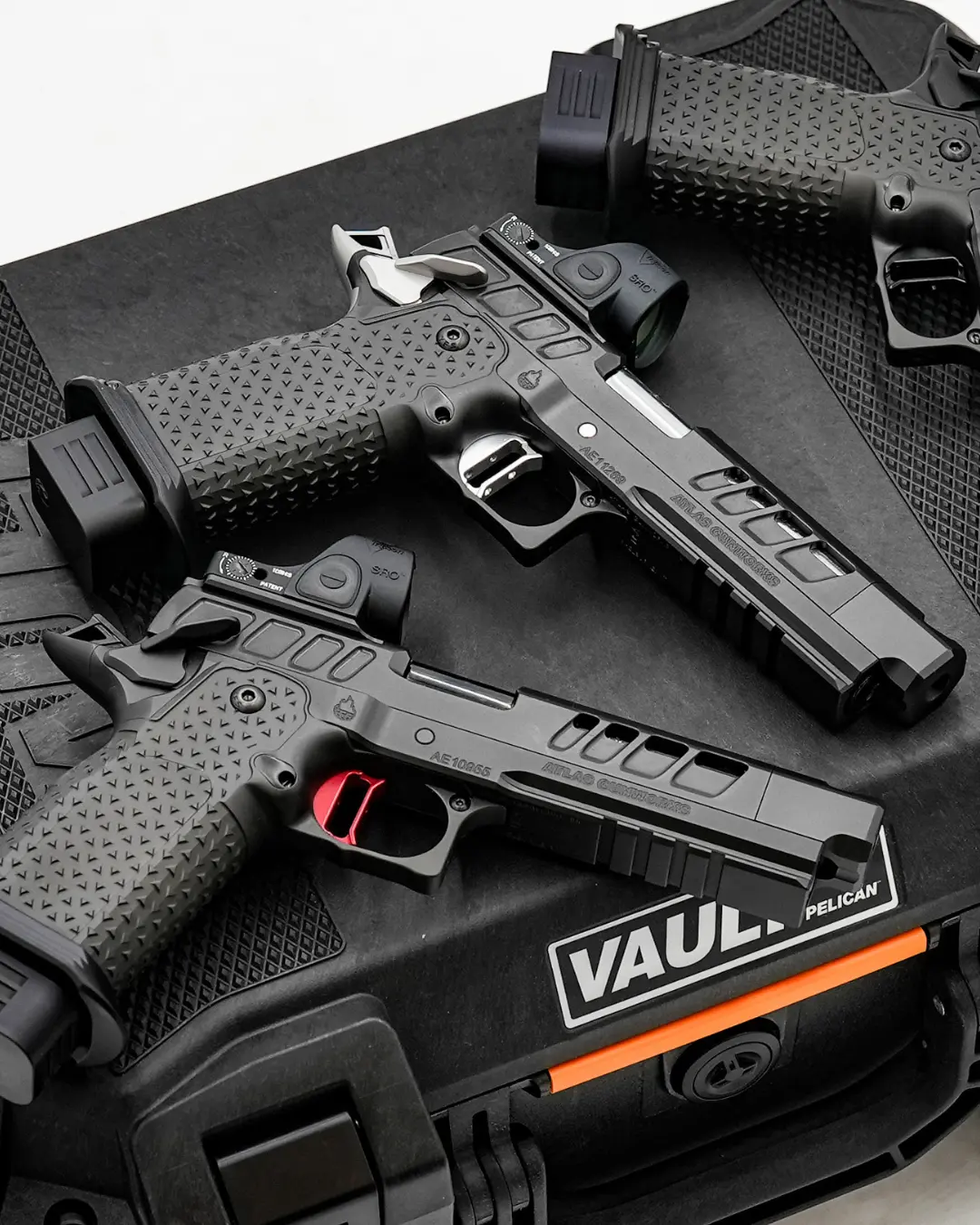 Three high-end black semi-auto handguns displayed on a tactical pistol case