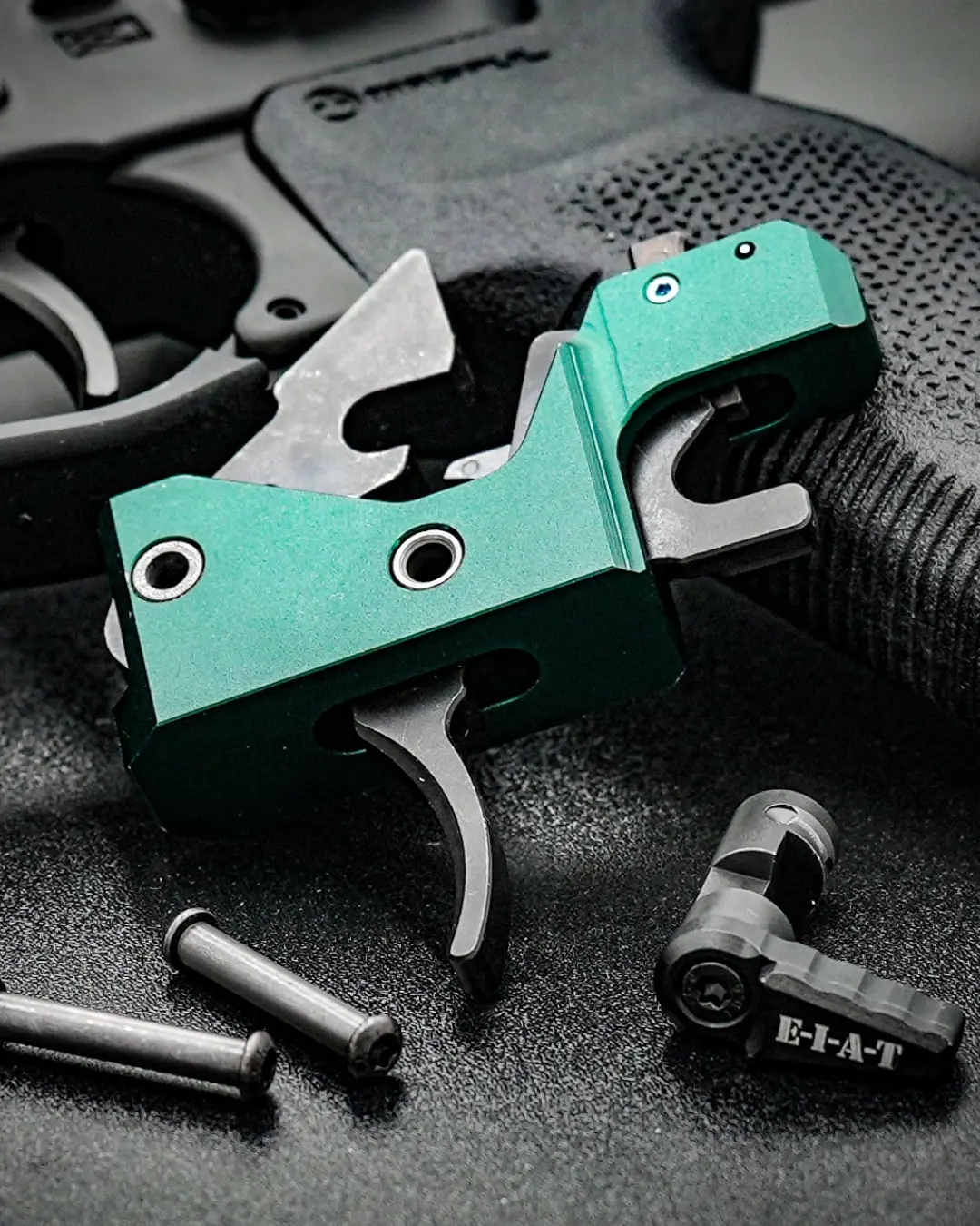 AR15 trigger assembly resting on a rifle pistol grip with spare gun parts